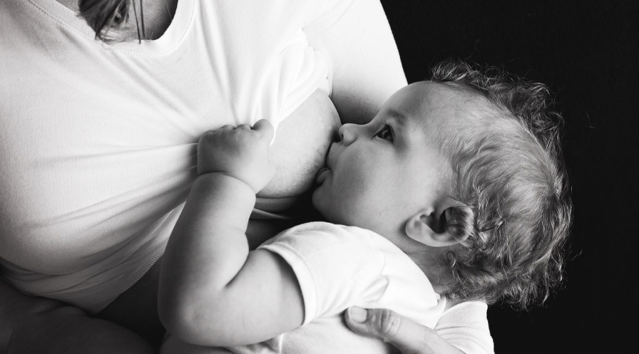Kobieta karmi piersią dziecko. Zdjęcie czarno/białe.